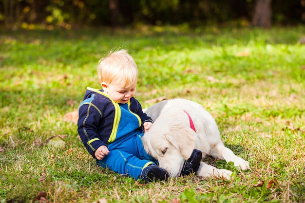O bebê feliz no gramado com seu cachorro
