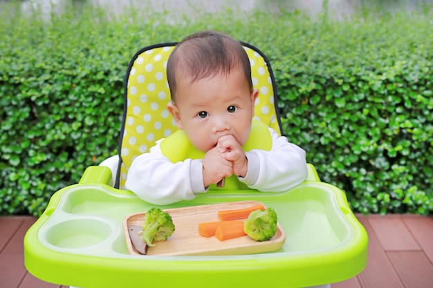 O bebê infantil asiático que come pelo bebê conduziu o desmame (BLW). Conceito de alimentos de dedo.