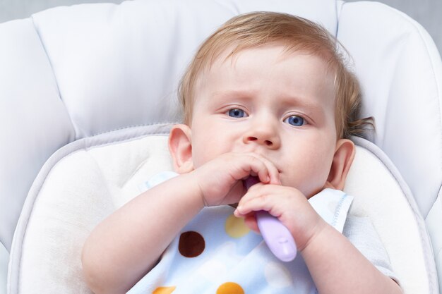 O bebê louro come a primeira atração. Segurando uma colher