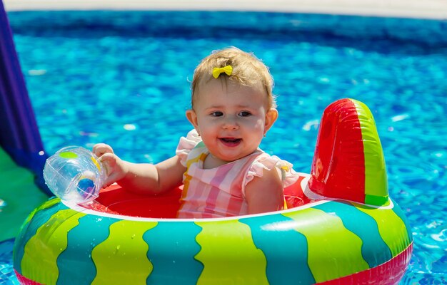 O bebê nada em círculo na piscina. Foco seletivo. Filho.