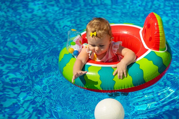 O bebê nada em círculo na piscina. Foco seletivo. Filho.