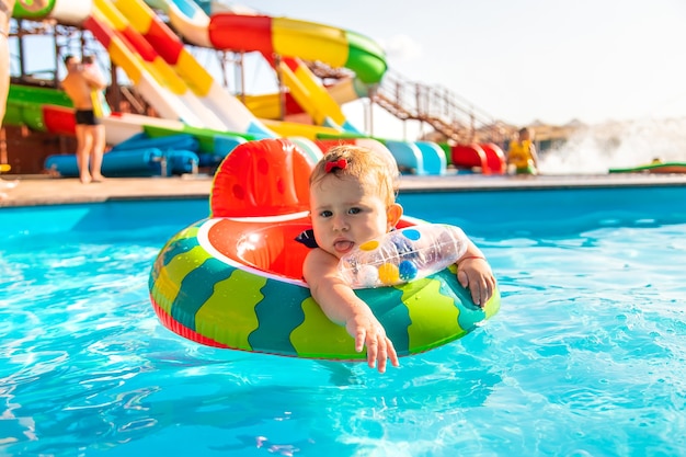 O bebê nada em círculo na piscina. Foco seletivo. Natureza.