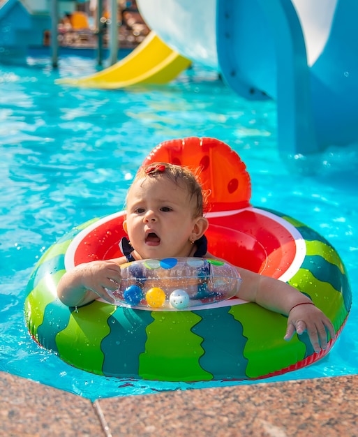 O bebê nada em círculo na piscina. Foco seletivo.