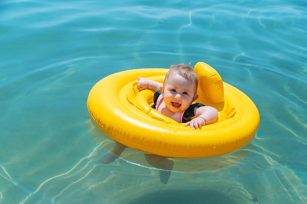 O bebê nada em círculo no mar. filho.