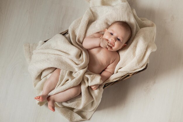 O bebê recém-nascido envolto em um cobertor de linho encontra-se em um berço de cesta de vime. produtos para crianças. conceito de sono saudável e desenvolvimento infantil. feliz infância e maternidade. Foto de alta qualidade
