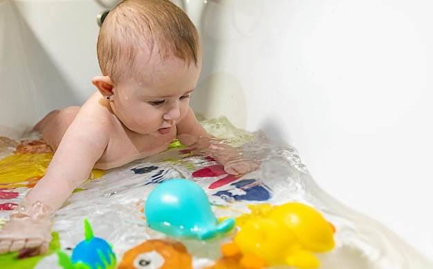 O bebê toma banho no foco seletivo do banho