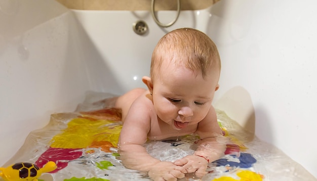 O bebê toma banho no foco seletivo do banho