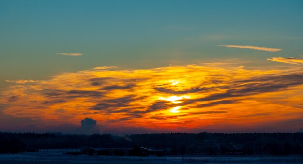 O belo pôr do sol com faixas no fundo do inverno de neve