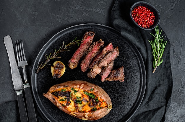 O bife marmorizado com batata doce cozida decora. Carne grelhada