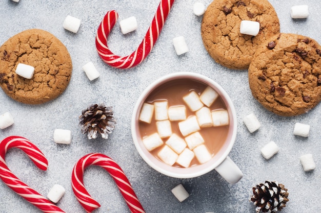 O biscoito de chocolate, caramelo de Natal, copo de chocolate e cones de marshmallow Decorações em um cinza. Fechar-se