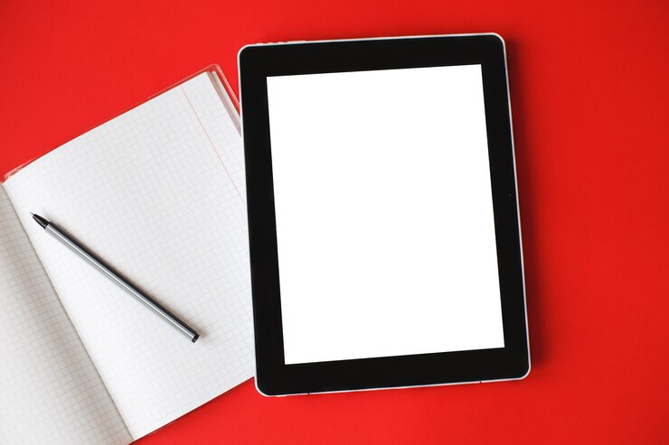 Foto o bloco de notas aberto da vista superior e um gadget com simulação sobre um fundo vermelho.