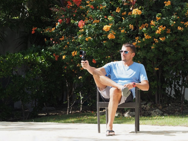 O blogueiro do resort está atirando na câmera. jardim florido tropical. selfie na câmera.