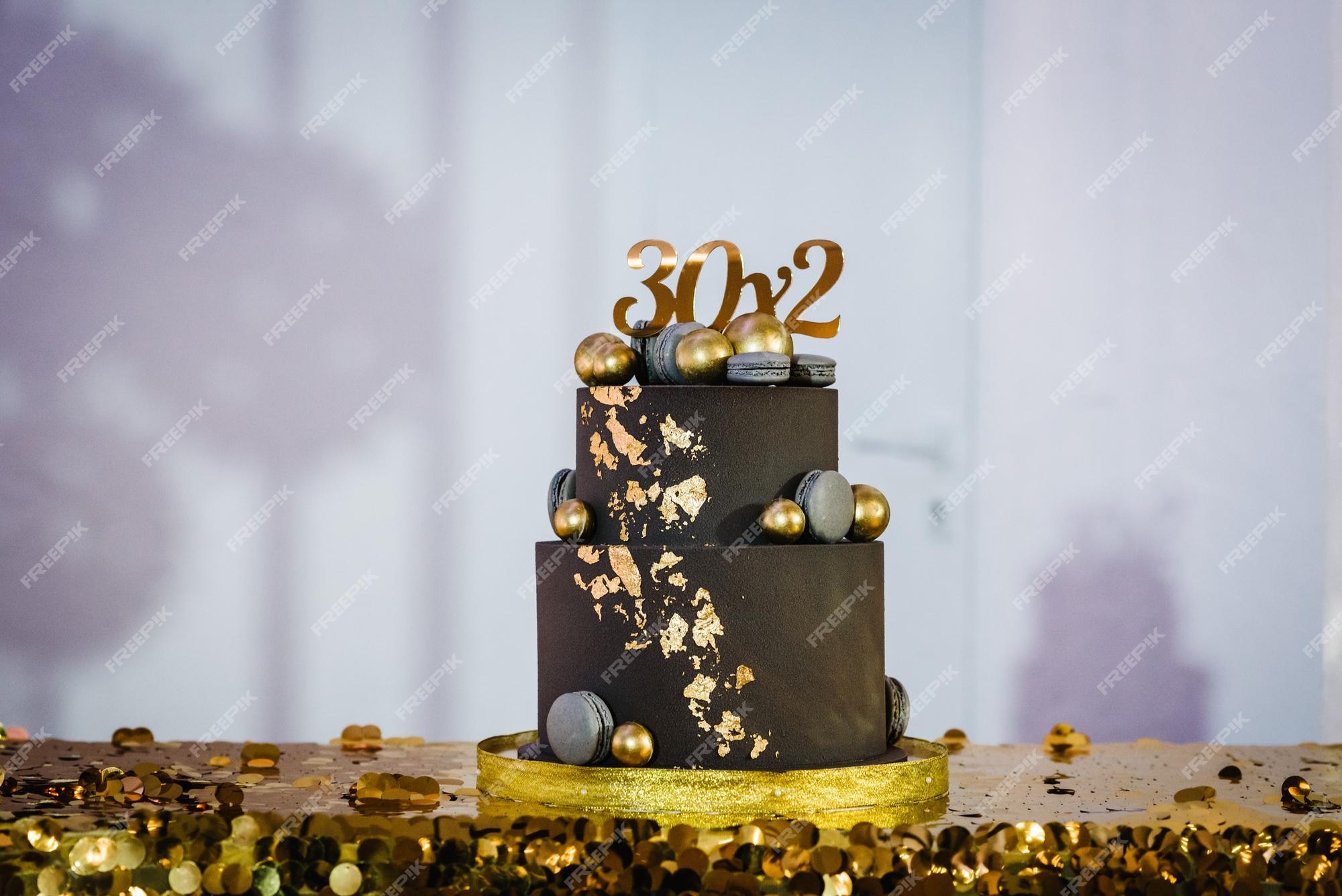 Mãos acendem velas no bolo o bolo de férias é decorado com bolas douradas,  brilhos dourados e macaroons pretos bolo de aniversário masculino 60 anos  fechar