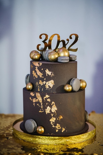 O bolo de férias é decorado com bolas douradas, brilhos dourados e macaroons pretos bolo de aniversário masculino 60 anos fechar