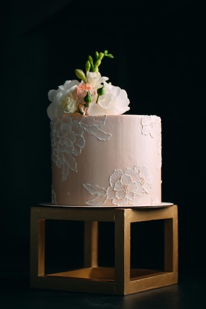 O bolo é decorado com flores em um fundo escuro.