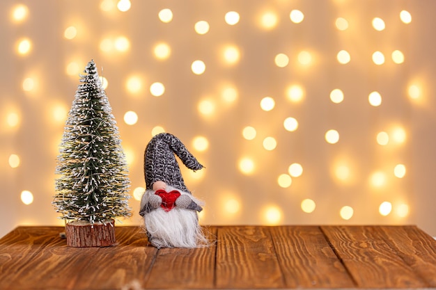 O boneco de neve do trenó do relógio da árvore de Natal vela presentes em um fundo de madeira e luzes de fundo