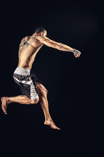 O boxeador atleta profissional em salto isolado no fundo do estúdio dsrk se encaixa na musculatura caucasiana