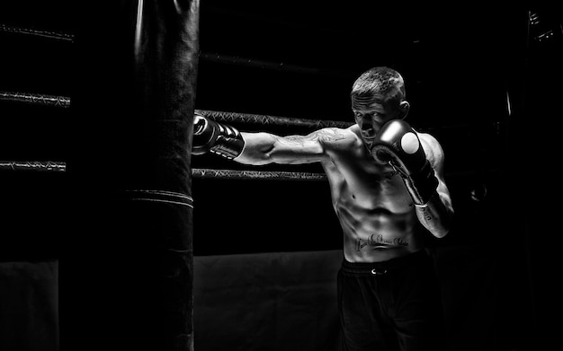 O boxeador profissional acerta o saco contra o fundo do ringue. vista lateral. o conceito de esporte e boxe clássico. mídia mista