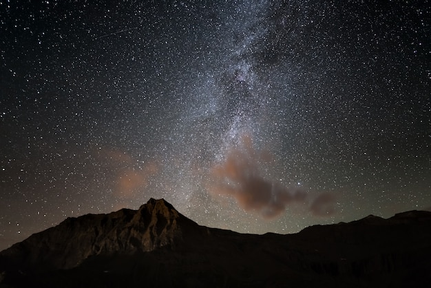 O brilhante colorido arco da via láctea e o céu estrelado do alto dos alpes