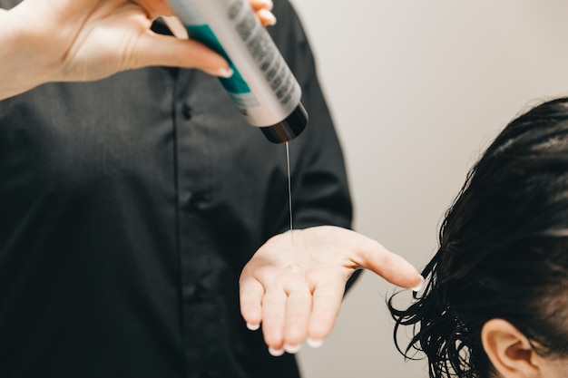 O cabeleireiro aplica o gel no cabelo de uma mulher em um salão de beleza