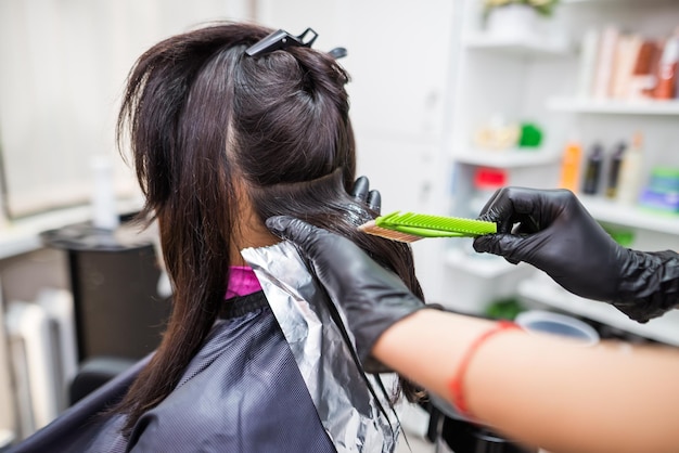 O cabeleireiro aplica queratina líquida profissional no cabelo do cliente Uma garota faz o fortalecimento da queratina do cabelo em um salão de beleza Cuidados com o cabelo