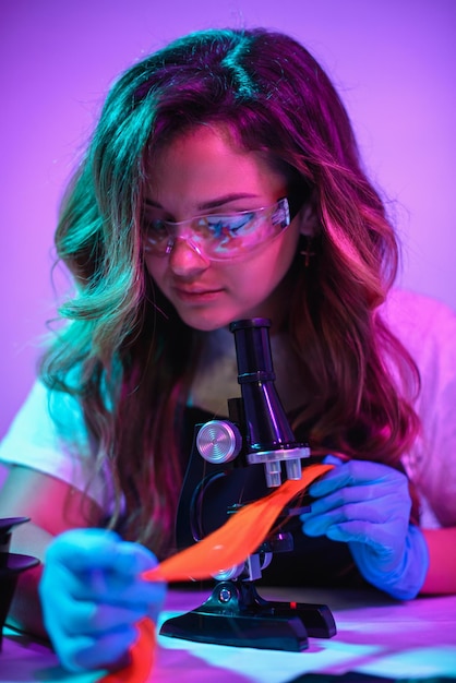 O cabeleireiro da mulher examina a estrutura do cabelo usando um microscópio. close-up, foco seletivo.