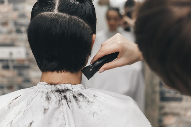 O cabeleireiro endireita o cabelo da menina após um corte de cabelo curto