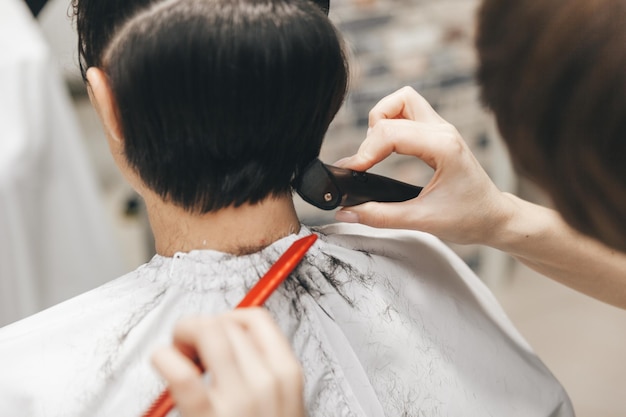 O cabeleireiro endireita o cabelo da menina após um corte de cabelo curto