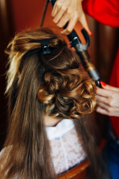 Foto o cabeleireiro faz da noiva um estilo de casamento com um curling ferro close up