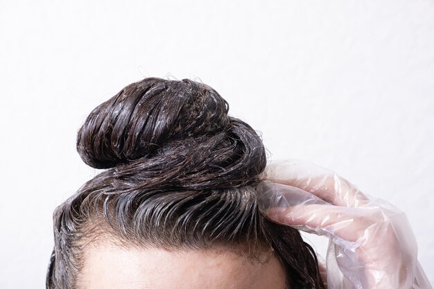 O cabelo das mulheres é coletado em um coque com tinta aplicada a ele Conceito de tingimento de cabelo