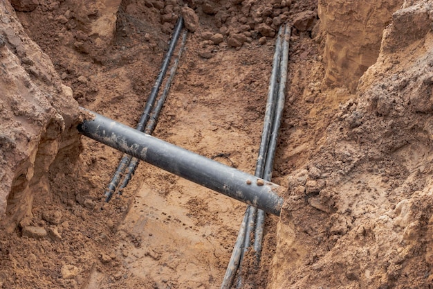 O cabo elétrico de alta tensão é colocado em uma vala sob as redes de esgoto de engenharia existentes Colocação de um cabo de alta tensão para fornecer eletricidade aos edifícios