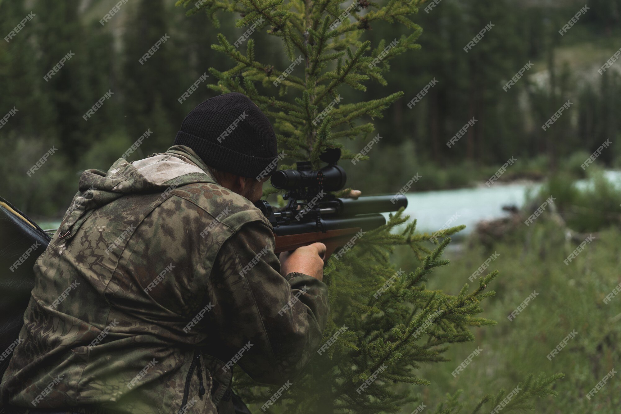 O caçador mira com um rifle. um homem camuflado está se preparando