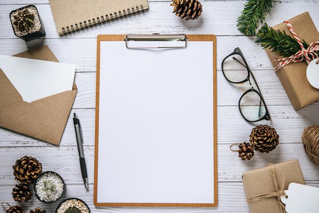 O caderno é colocado em uma mesa de madeira branca com canetas de copo e cones de pinheiro secos