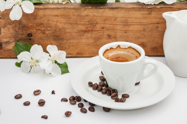 O café da manhã com árvore de maçã floresce na tabela branca no jardim.