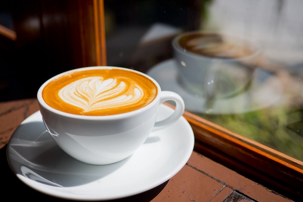 o café quente da arte do latte na tabela de madeira, relaxa o tempo