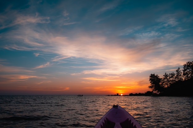 O caiaque e a silhueta do barco de pesca no por do sol