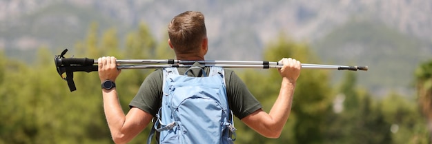 O caminhante do homem está segurando bengalas finlandesas no topo do conceito de caminhada e saúde na montanha