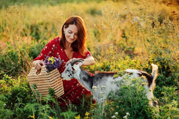 O campo melhora a saúde mental Saúde mental rural Pausa relaxante no campo na casa rural Mulher de vestido alimentando cabras no gramado