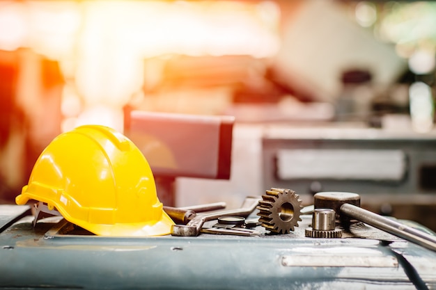 O capacete de segurança amarelo do capacete com instrumentos alinha ferramentas na fábrica para o fundo.