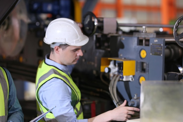 O capataz ou trabalhador trabalha no local da fábrica verifica a máquina ou os produtos no local Engenheiro ou técnico verificando o material ou a máquina na planta industrial e na fábrica