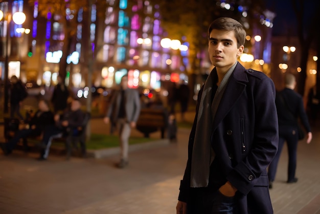 O cara anda pela cidade à noite. Retrato de um jovem engraçado.
