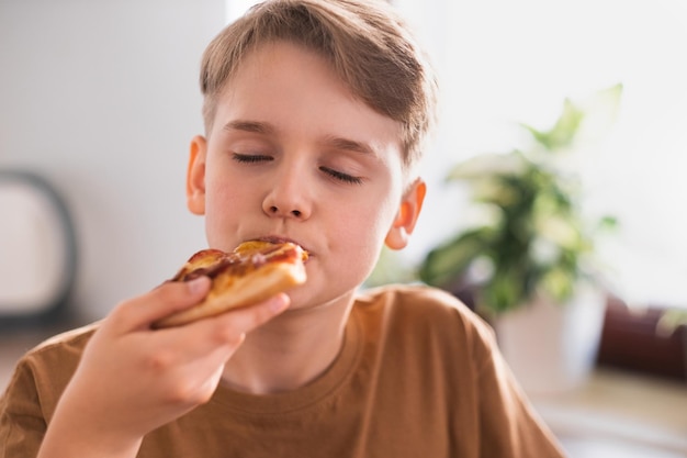 O cara com prazer come uma deliciosa pizza na cozinha em casa