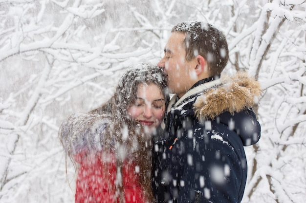 O cara e a garota descansam na floresta de inverno marido e mulher na neve casal jovem caminhando no parque de inverno