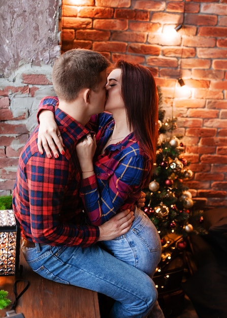 O cara e a garota estão se abraçando na janela. Um casal apaixonado se alegra na véspera de Ano Novo. História de amor de ano novo