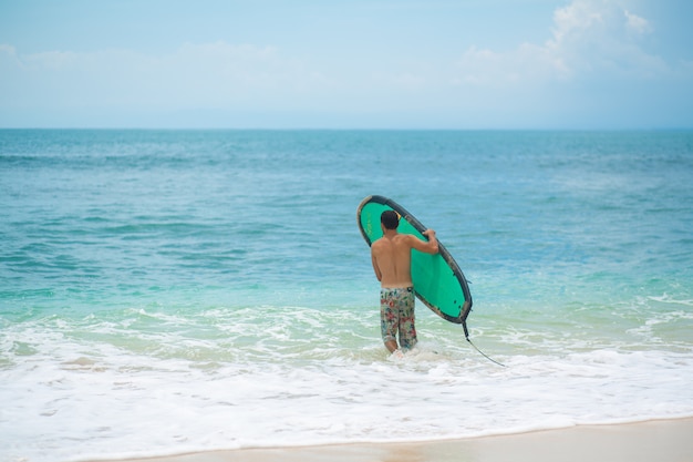 O cara está nadando na prancha de surf no oceano. Estilo de vida ativo e saudável na vocação de verão.