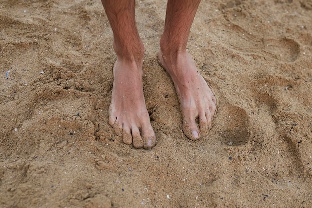 O cara fica na areia com os pés descalços de perto