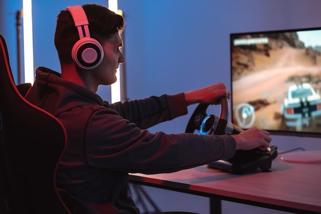 O cara jogador com fones de ouvido jogando videogame em seu computador pessoal