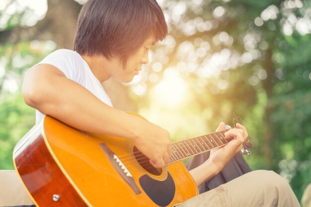 O cara tocando violão, ao ar livre, calças cargo