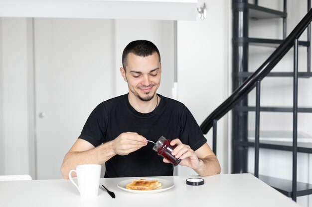 O cara toma café da manhã com torradas com geléia.