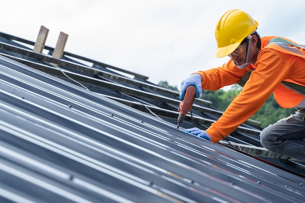O carpinteiro da construção usa inspeção uniforme de segurança e instala trabalhos de cobertura metálica para o telhado industrial.